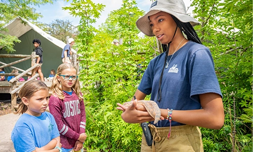 camp counselor holding snake with campers