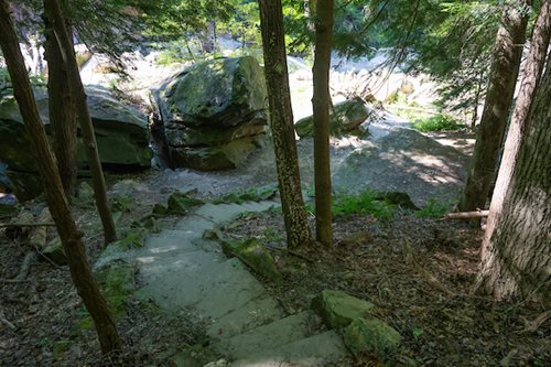 A tranquil path winding through a forest, surrounded by trees and rocky terrain, perfect for a peaceful walk.
