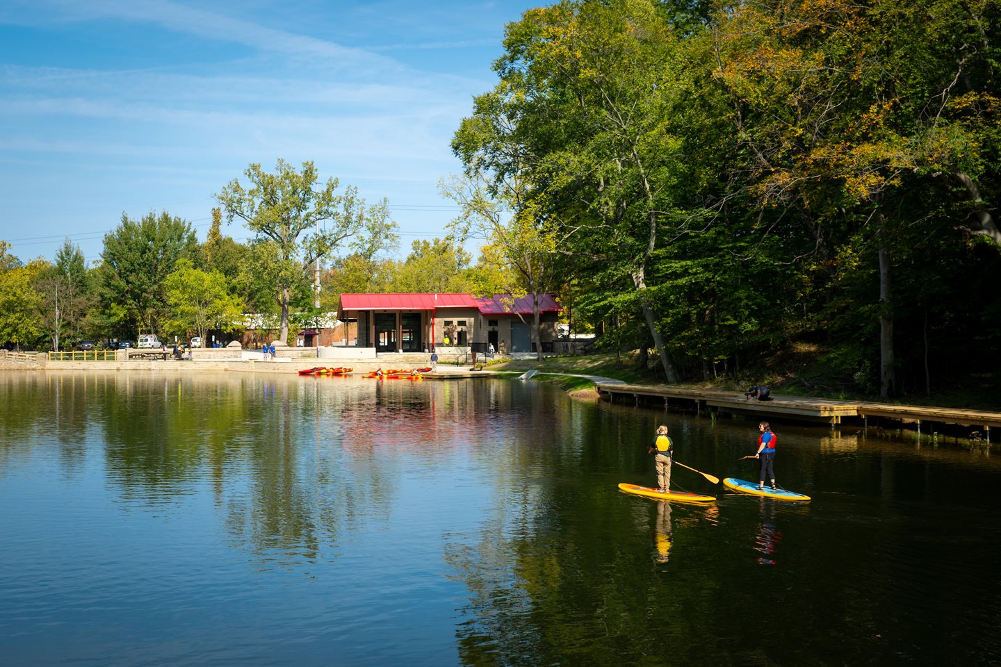 A boathouse on a lake and paddleboarders